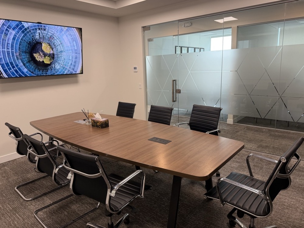 Boardroom with conference table, wall-mounted display and frosted-glass entry