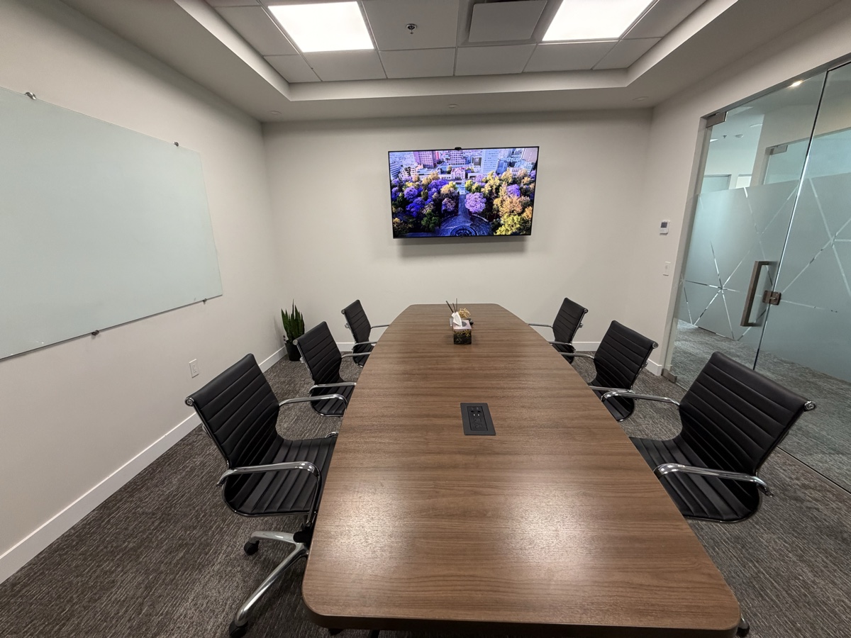 Boardroom seen from the far end, whiteboard wall and full-length table