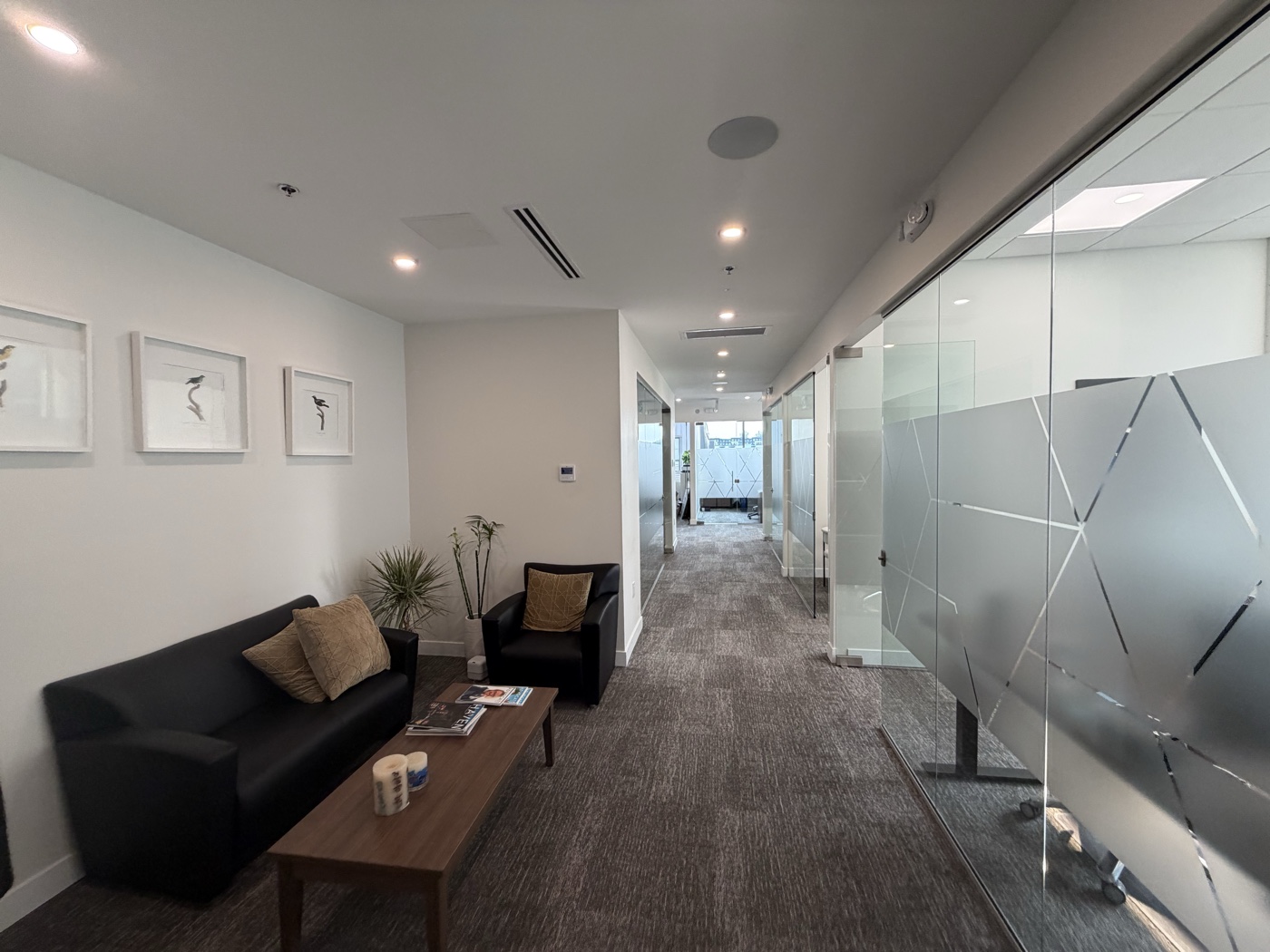 Waiting room with leather sofa, armchair and coffee table by the glass corridor