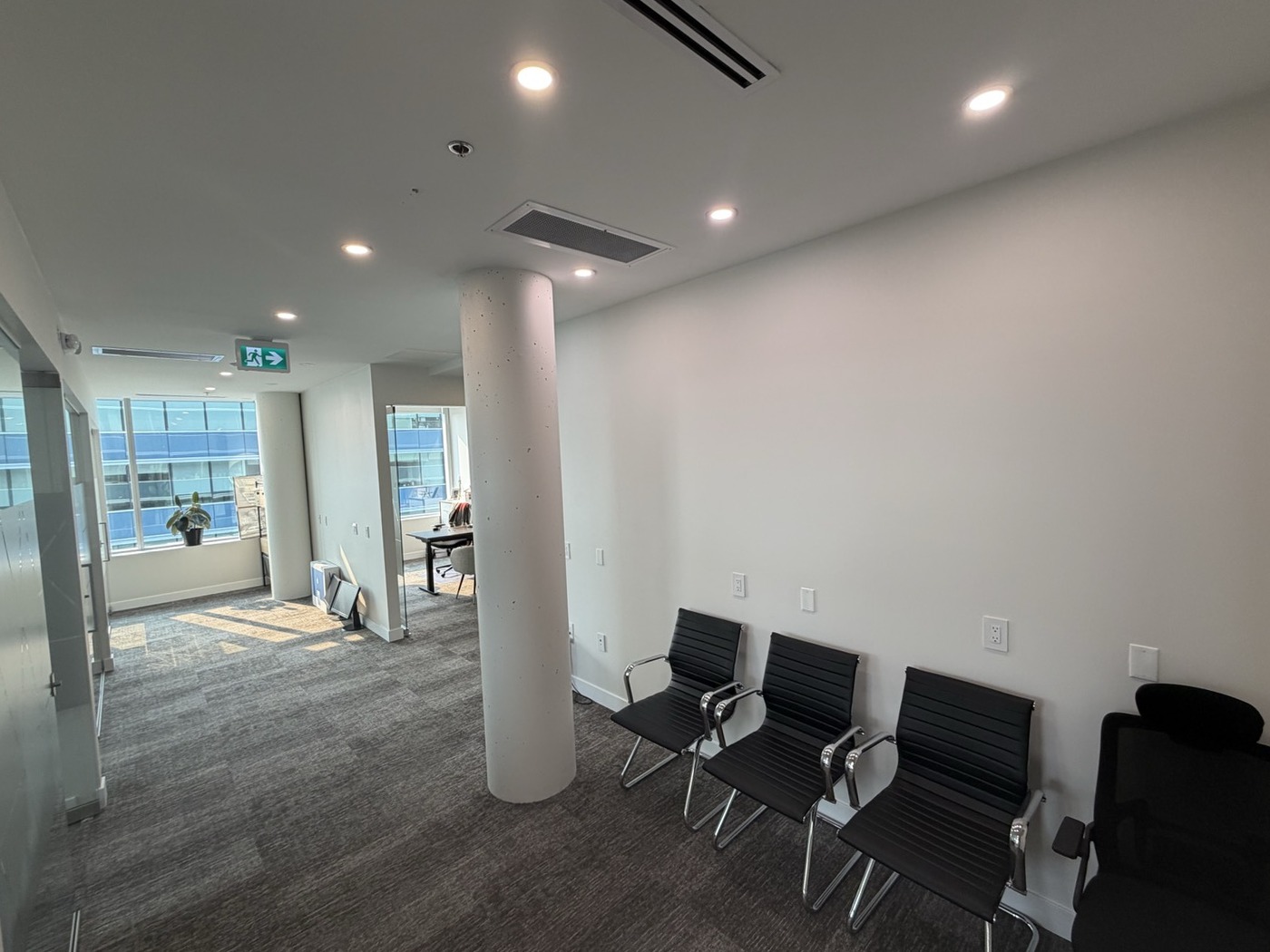 Corridor near the kitchen with visitor seating and natural light from the end windows